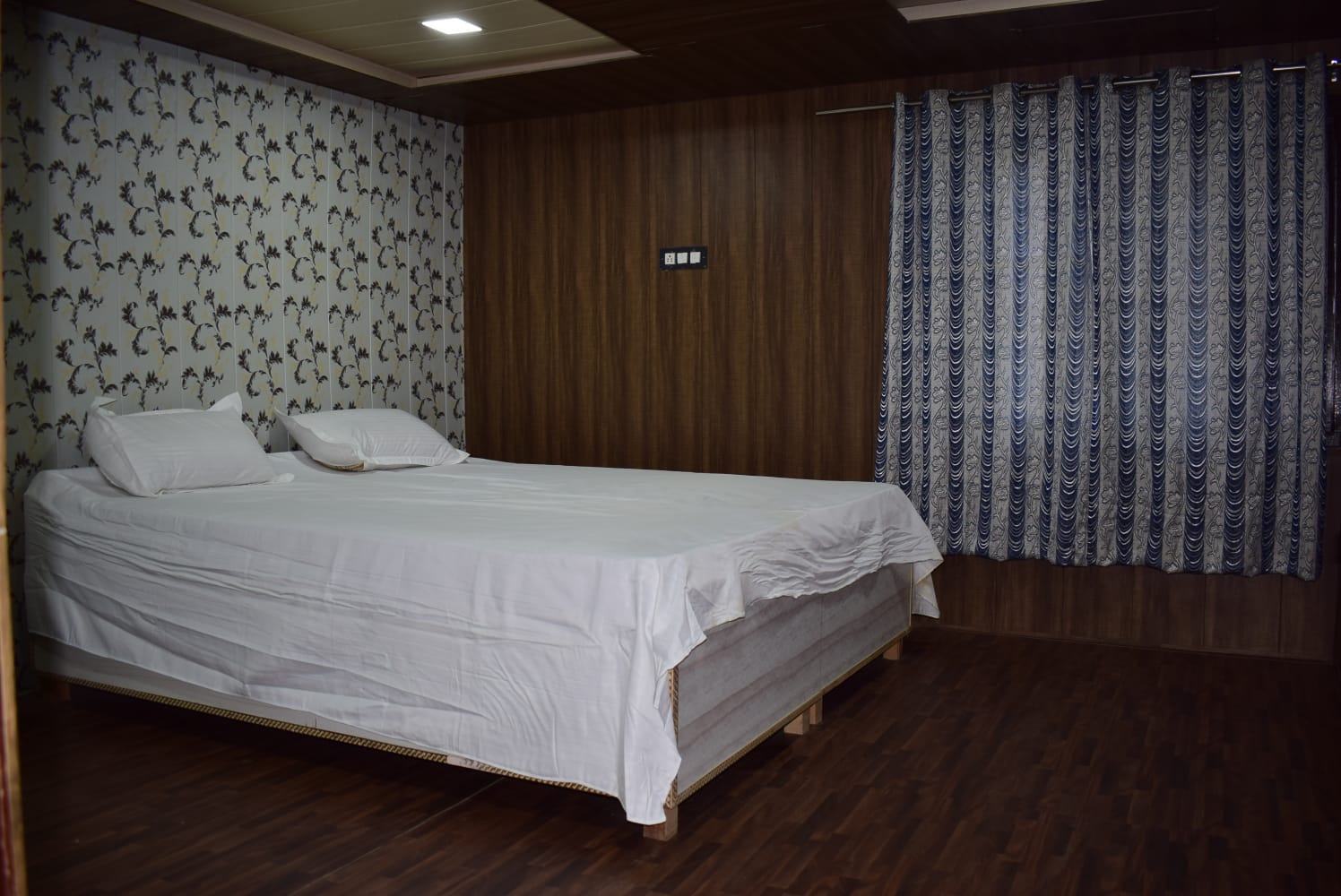 Spacious bedroom with comfortable double bed and floral wallpaper